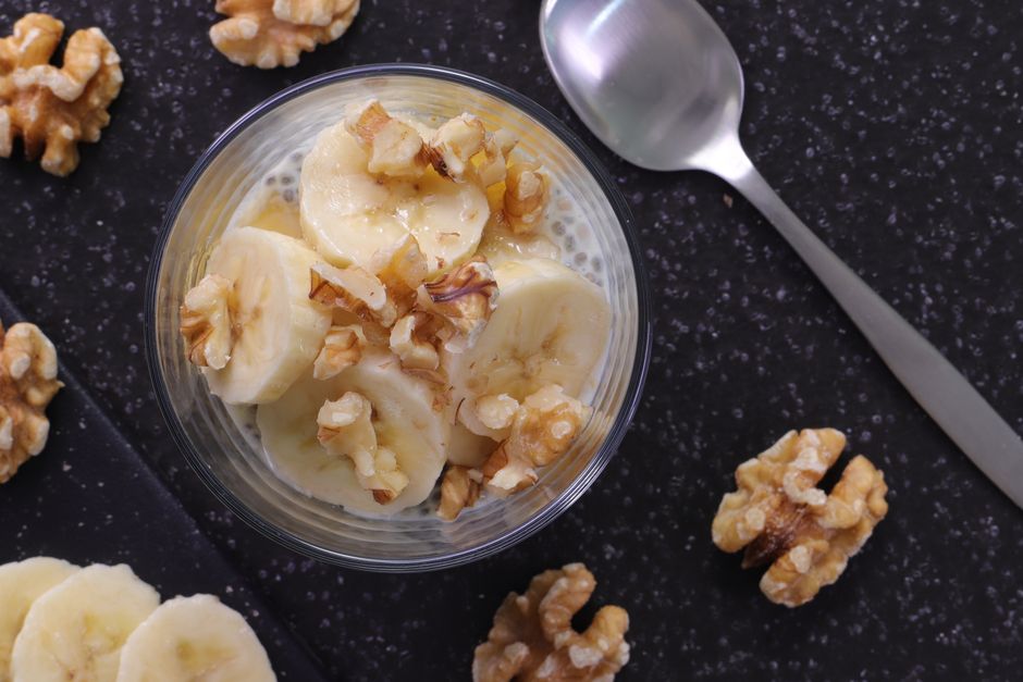 A deep dish of homemade Southern banana pudding with layers of vanilla custard, sliced bananas, and vanilla wafers, topped with swirls of fresh whipped cream and crushed cookie crumbs