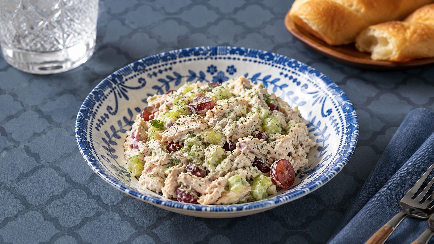 Classic homemade chicken salad served on a toasted croissant with lettuce, photographed on a white plate with a side of crackers