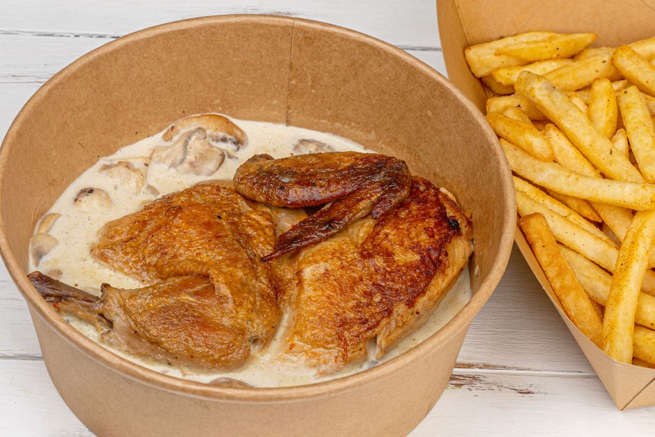 A Dutch oven filled with classic coq au vin —? golden chicken thighs and drumsticks nestled in a deep red wine sauce with mushrooms, pearl onions, and bacon, garnished with fresh parsley