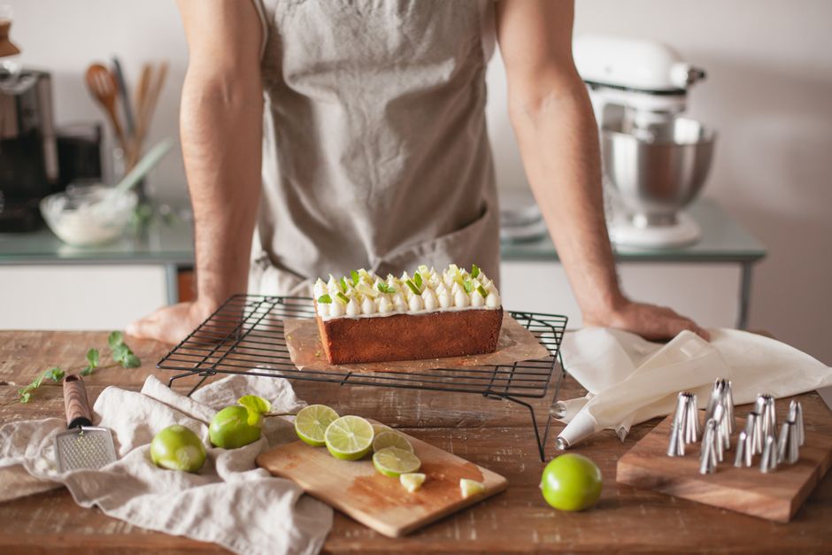 A slice of classic key lime pie with a golden graham cracker crust, bright pale-yellow filling, and a swirl of whipped cream on a white plate