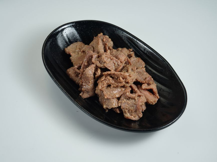 Close-up of Korean beef bulgogi in a cast iron skillet, caramelized and glossy, garnished with sesame seeds and sliced green onions, served over steamed white rice