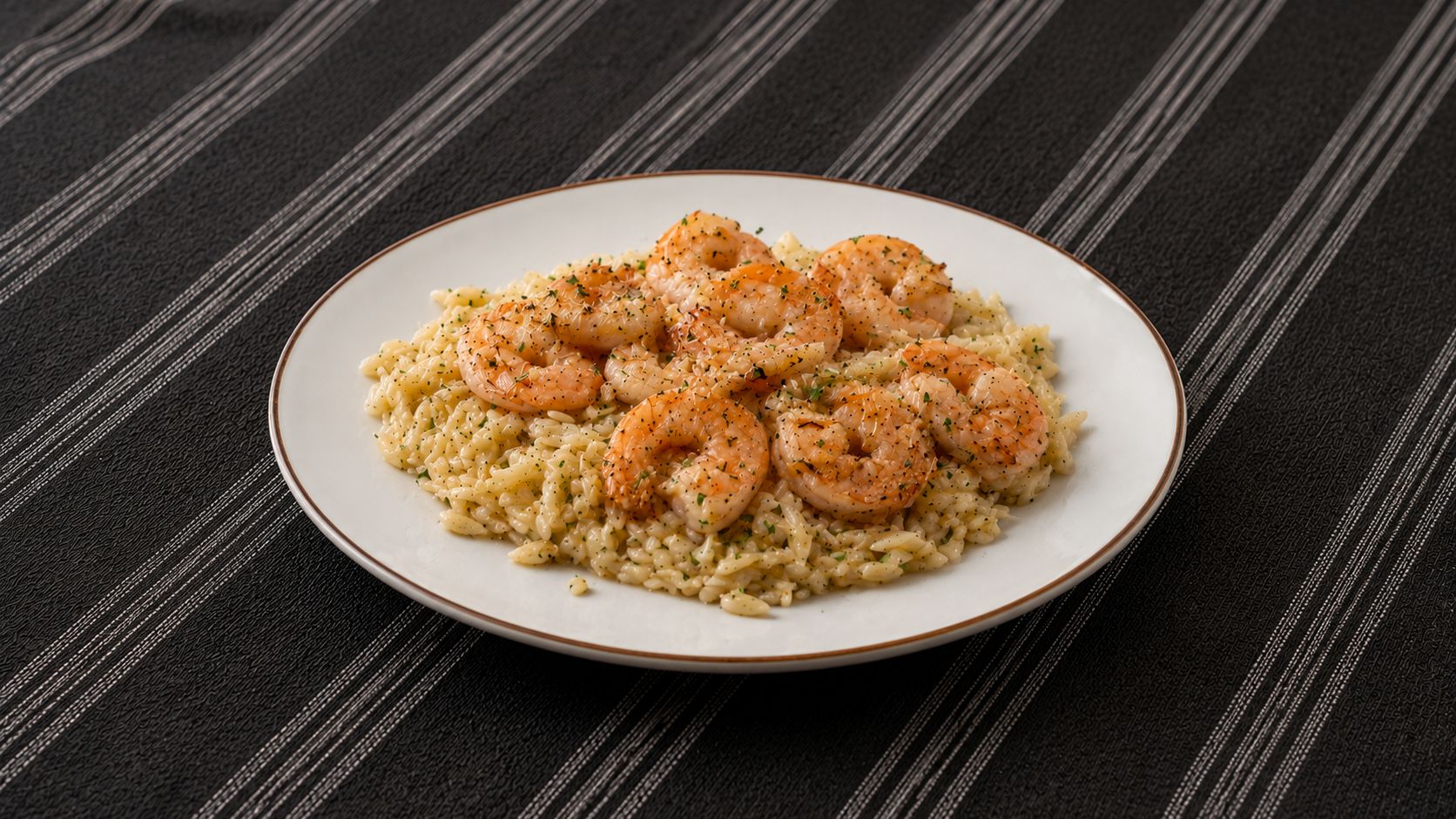 Garlic butter shrimp pasta in a wide white bowl, topped with fresh parsley and Parmesan, with a lemon wedge on the side