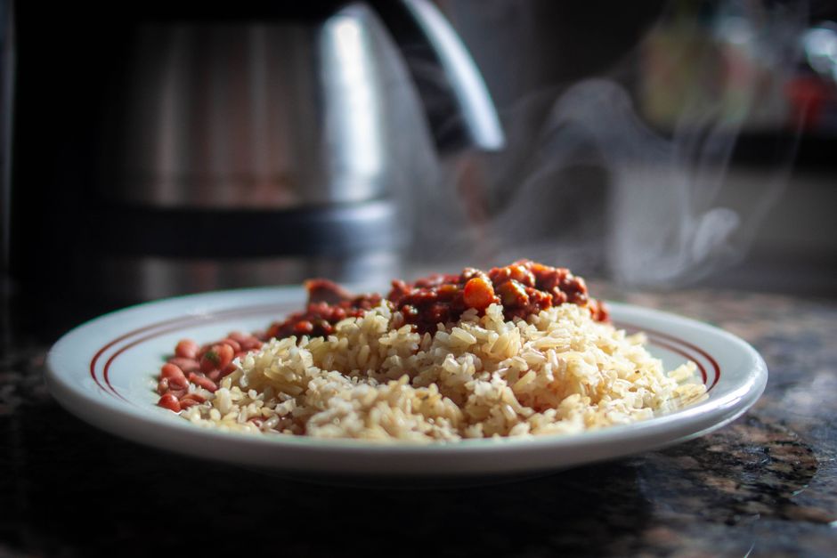 A rustic bowl of classic rice and beans garnished with fresh cilantro and lime wedges on a wooden table